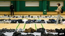 FILE - A journalist walks amongst personal belongings retrieved from the scene of a fatal Halloween crowd surge that killed more than 150 people in the Itaewon district, in Seoul, South Korea.