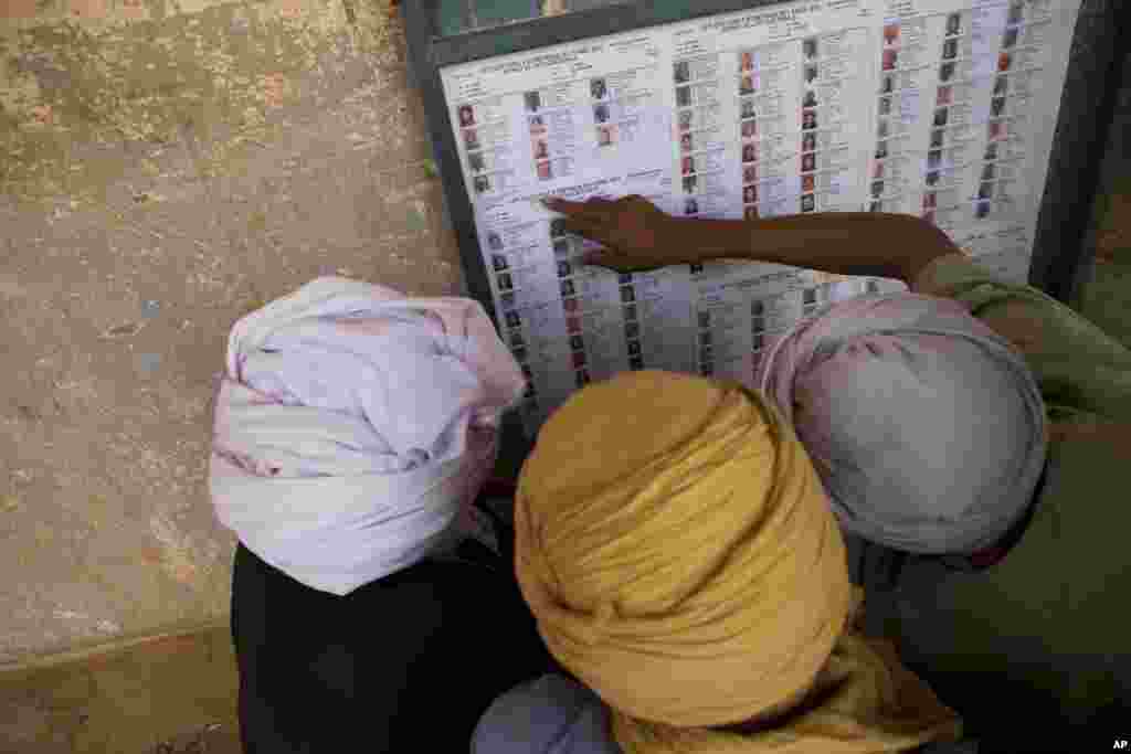 Men search for their names on a list of registered voters outside a polling station in Kidal, Mali, shortly after the opening of polls, July 28, 2013. 