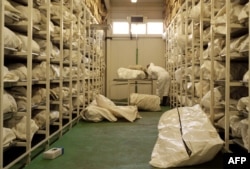FILE - A pathologist uncovers one of some 4,000 body bags kept inside a giant refrigerator in Tuzla, Bosnia and Herzegovina, July 1, 2004. The bags contain the remains of the bodies of Muslim men and boys from the eastern Bosnian town of Srebrenica who were massacred in in 1995.