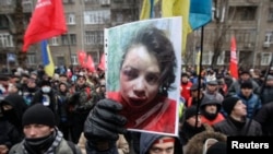 A protester holds a picture of journalist Tetyana Chornovil, who was beaten and left in a ditch just hours after publishing an article on the assets of top government officials, during a protest rally in front of the Ukrainian Ministry of Internal Affairs, Dec. 25, 2013.