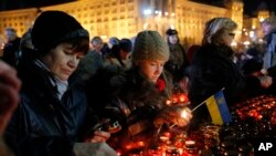 Ukrainians light candles during a rally in Kyiv, Ukraine, Friday, Nov. 21, 2014. 