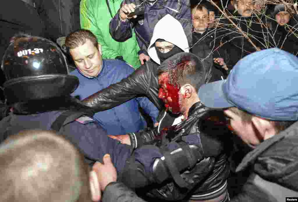 Police officers escort a wounded participant of an anti-war rally during clashes with pro-Russia demonstrators in Donetsk, Ukraine, March 13, 2014.