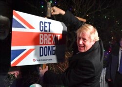 Britain's Prime Minister and Conservative party leader Boris Johnson poses as he hammers a "Get Brexit Done" sign into the garden of a supporter, in Benfleet, east of London on Wednesday, Dec. 11, 2019, the final day of campaigning for the general…