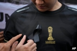 Seorang aktivis memasang pita hitam di dadanya dalam aksi unjuk rasa menentang pembatalan Piala Dunia U-20 FIFA, di Jakarta, Jumat, 31 Maret 2023. (AP/Dita Alangkara)