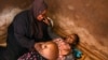 FILE - A traditional birth attendant attends to a pregnant woman at her home, in Simika Village, Chiradzulu, southern Malawi, May 23, 2021. 