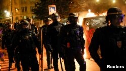 A group of police officers walk as people protest following the death of Nahel, a 17-year-old teenager killed by a French police officer in Nanterre during a traffic stop, and against police violence, in Paris, France, June 30, 2023. 