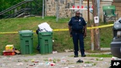 Seorang petugas polisi berdiri di area insiden penembakan massal di Distrik Selatan Baltimore, 2 Juli 2023.
