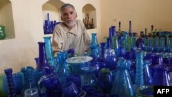 FILE - In this Aug. 12, 2024, photo, Afghan glassblower Ghulam Sakhi Saifi looks on while arranging glassware at his shop in Afghanistan's western city of Herat.