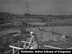 A worker views construction of the Fort Loudon Dam in Tennessee, built by the TVA to bring electricity and flood control to the Tennessee Valley. Photo taken June 1942.