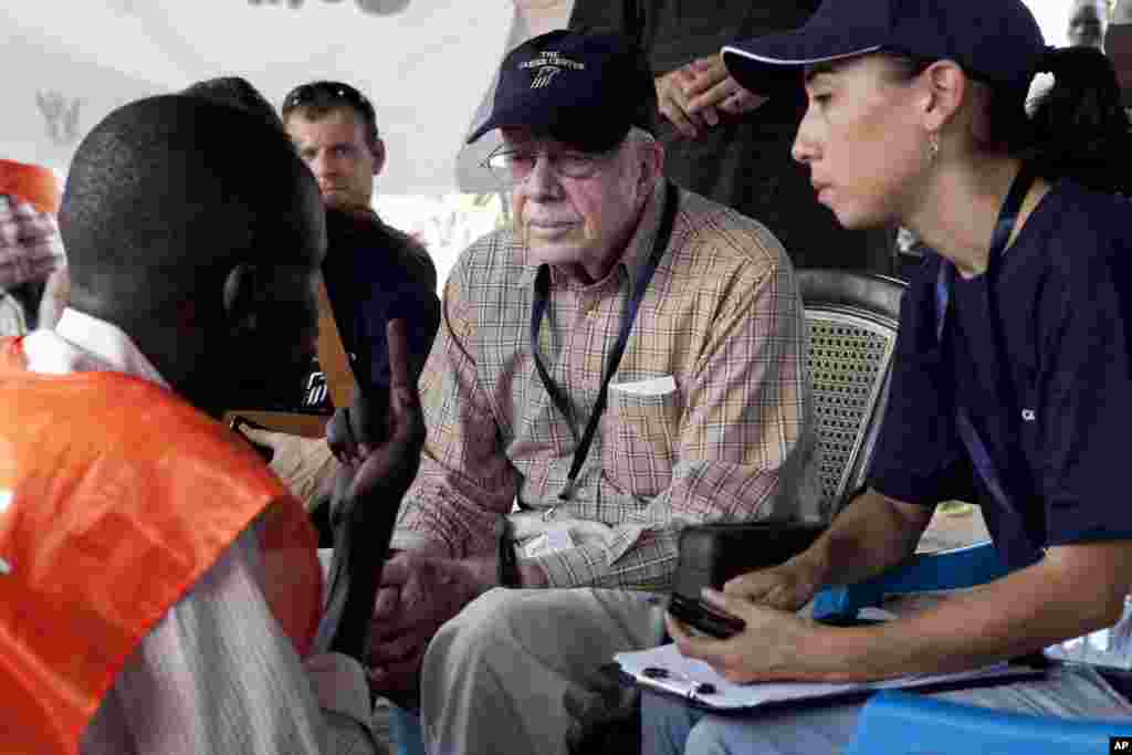 FILE - Former U.S. President Jimmy Carter speaks with a polling official at a polling station outside Juba, southern Sudan, April 13, 2010. Carter's organization, the Carter Center, deployed a team of observers for the elections. Widespread problems with voting prompted Sudanese authorities to extend the voting period from three to five days. 