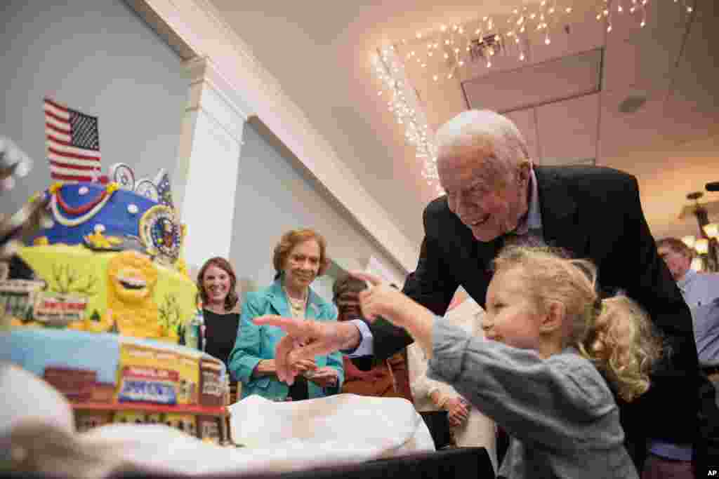 Former first lady Rosalynn Carter, left, looks on as former President Jimmy Carter and grandson Errol, 4, look at a birthday cake during his 90th birthday celebration held at Georgia Southwestern University, Oct. 4, 2014, in Americus, Georgia.