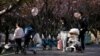 Parents push strollers with their babies in a park in Shanghai, China, April 2, 2023.