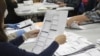 FILE - An election worker examines a ballot on May 19, 2022, in Oregon City, Ore. 