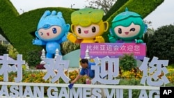 A staff member cleans an Asian Games sign ahead of the 19th Asian Games in Hangzhou, China, Sept. 21, 2023.