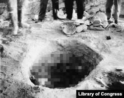 This circa 1925 photograph shows presumed archaeologists standing above an excavated grave in Pueblo Grande, Nevada.