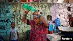 FILE - A woman pours water on her head after filling her containers with drinking water from a municipal tanker on a hot summer day in New Delhi, India, May 21, 2024.