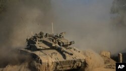 An Israeli soldier moves on the top of a tank near the Israeli-Gaza border, as seen from southern Israel, July 14, 2024. 