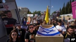 Hagit and Ruby Chen, left, carry an empty casket during a mock funeral for Israelis whose remains are being held by Hamas militants in the Gaza Strip, near the Israeli parliament building in Jerusalem, May 9, 2024. 