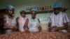 FILE - Workers at Moments Chocolate workplace remove husks from cocoa beans on June 18, 2019 in Accra. 