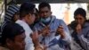 FILE: Migrants get help with the CBPOne app from a Tijuana, Mexico, city worker, Jan. 24, 2023, in Tijuana, Mexico.