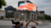 FILE - Men rest near a screen depicting a phoenix at a mall in Beijing, June 11, 2024. China kept a key lending rate unchanged June 17 as data showed signs of persistent weakness in manufacturing and the real estate sector.