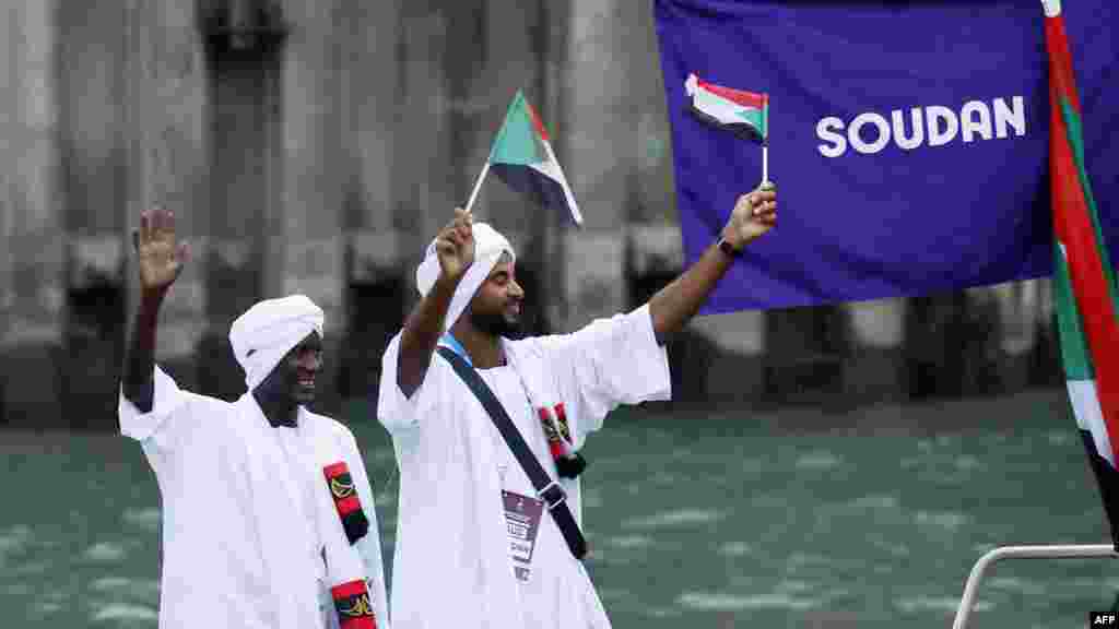 Atlet delegasi Sudan mengibarkan bendera di atas perahu dalam parade terapung di sungai Seine saat upacara pembukaan Olimpiade 2024 di Paris, 26 Juli 2024. (Foto: Clodagh Kilcoyne / POOL / AFP) 