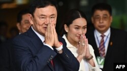 Paetongtarn Shinawatra (kanan) mendampingi ayahnya, mantan Perdana Menteri Thaksin Shinawatra, setibanya di Bandara Don Mueang, Bangkok, Thailand, 22 Agustus 2023. Shinawatra kembali ke negaranya setelah 15 tahun dalam pengasingan. (Foto: Lilian Suwanrumpha/AFP)