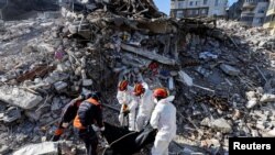 Tim SAR mengangkat jenazah korban yang diambil dari reruntuhan bangunan yang hancur akibat gempa di Antakya, Turki, 17 Februari 2023. (REUTERS/Nir Elias)