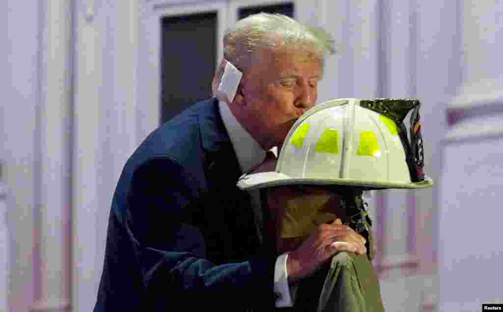 Republican presidential nominee Donald Trump kisses the turnout coat and helmet of former Buffalo Township Volunteer Fire Department chief Corey Comperatore, who was killed at his rally last week, on Day 4 of the RNC at the Fiserv Forum in Milwaukee, July 18, 2024. 