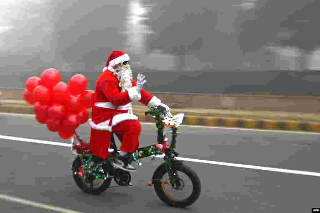 Santa Claus rides a cycle along a street engulfed in fog on Christmas in New Delhi, India, Dec. 25, 2023.
