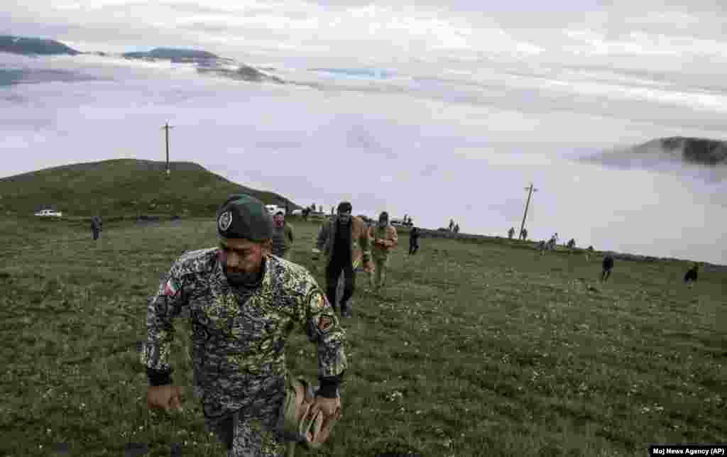 In this photo provided by Moj News Agency, rescue team members search for the wreckage of the helicopter carrying Iranian President Ebrahim Raisi after it crashed in Varzaghan in northwestern Iran, May 20, 2024.