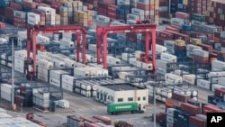 FILE - A cargo truck drives amid stacked shipping containers at the Yangshan port in Shanghai, China, March 29, 2018.