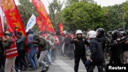 People react after riot police used tear gas during clashes, as protesters attempt to defy a ban and march on Taksim Square to celebrate May Day in Istanbul, May 1, 2024. 