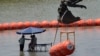 Workers take a break from deploying large buoys to be used as a border barrier along the banks of the Rio Grande in Eagle Pass, Texas, July 12, 2023. The floating barrier is being deployed in an effort to block migrants from entering Texas from Mexico.