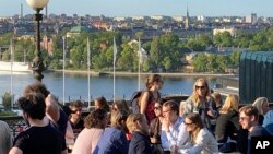 People enjoy drinks and snacks in the evening sun on a terrace overlooking Stockholm, on May 30, 2023.