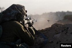 Seorang tentara Israel menembakkan senjatanya selama operasi darat yang sedang berlangsung oleh tentara Israel terhadap kelompok Islam Palestina Hamas, di Jalur Gaza. (Foto: via Reuters)