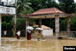 FILE - People wade through flood water amid severe flooding in the Fazilpur area of Feni, Bangladesh, Aug. 26, 2024.