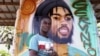 Le peintre ivoirien Lopoa Kouassi Bi "LK" pose pour un portrait devant un "Massa", un taxi partagé décoré, à Yamoussoukro le 25 janvier 2024.