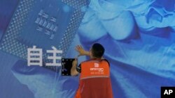 一名工人在上海举办的世界人工智能大会上检查中国科技公司中科曙光展示的芯片和自主字样的屏幕。（2023年7月5日）