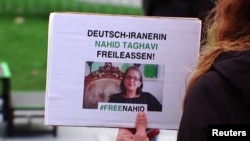 Potongan gambar dari sebuah video menunjukkan seorang demonstran memegang poster berisi tuntutan pembebasan warga Jerman keturunan Iran Nahid Taghavi, yang kini dipenjara di Iran, dalam sebuah aksi di Berlin, Jerman, pada 22 Februari 2023. (Foto: Reuters)
