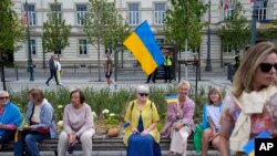 Люди з українськими прапорами у Вільнюсі в Литві, де станом на серпень 2023 р. зареєстровані понад 72 000 біженців від російської війни в Україні. Фото 11 липня 2023 р.