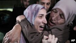 Shuruq Dwayat (kiri), warga Palestina yang ditahan oleh Israel dan akhirnya dibebaskan, dipeluk oleh kerabatnya saat ia tiba di rumahnya di Sur Bahar, Yerusalem timur, pada 26 November 2023. (Foto: AP/Mahmoud Illean)