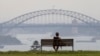 FILE - A man watches the sunset from a park bench in the Eastern suburbs of Sydney, Nov. 16, 2020. 