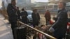 FILE - Migrant workers with their luggage take a break outside the West Railway Station before catching their trains in Beijing, Jan. 6, 2023.