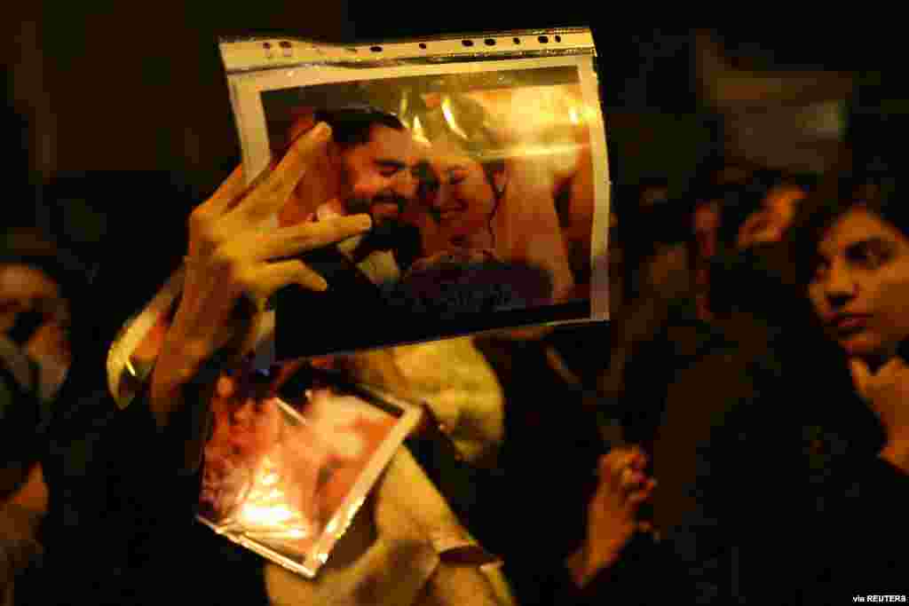 A woman holds a picture of newlyweds, victims of the crash of a Ukraine International Airlines plane, as people gather to show their sympathy in Tehran, Iran, Jan. 11, 2020.