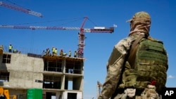 Seorang tentara Rusia menjaga lokasi gedung apartemen baru yang sedang dibangun dengan dukungan Kementerian Pertahanan Rusia, di Mariupol, di wilayah di bawah kendali Pemerintah Republik Rakyat Donetsk. (Foto: AP)
