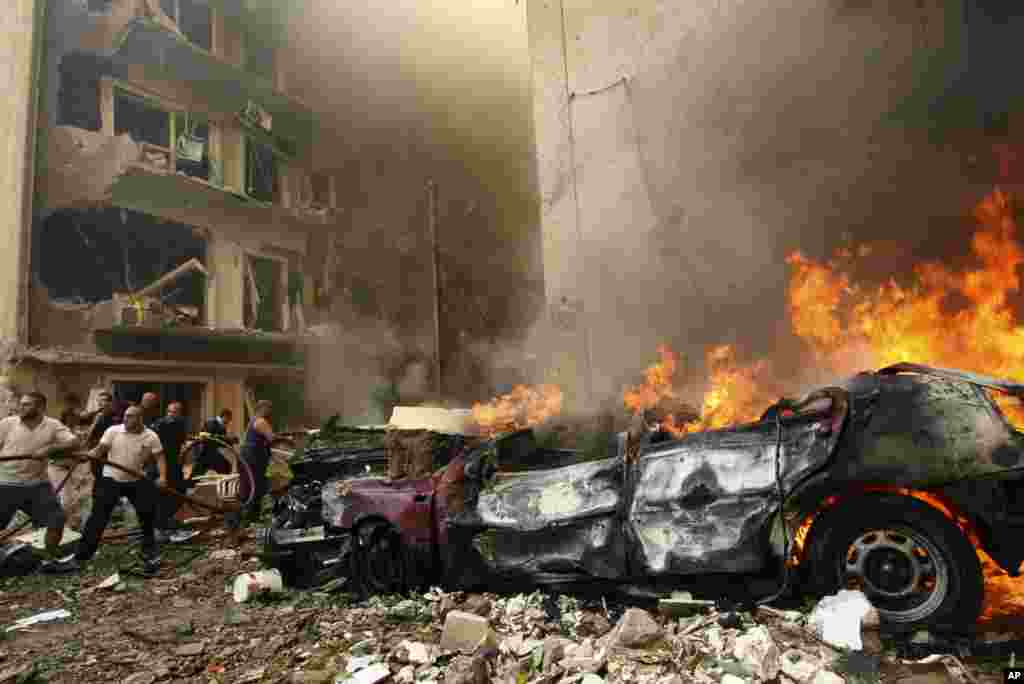Firefighters try to extinguish a fire as a car burns at the scene of an explosion in Ashafriyeh, central Beirut, October 19, 2012.