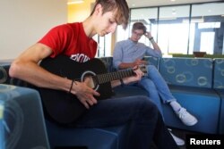 Ukrainian students Hlib Burtsev plays his guitar as Oleksii Shebanov sings along in the common area of their dorm ahead of their first year at Brown University in Providence, Rhode Island, U.S., August 16, 2022. REUTERS/Brian Snyder