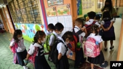 Students wearing face masks form a line as they enter their classroom during the opening of classes at a school in Quezon City, suburban Manila on Aug. 22, 2022, as millions of children in the Philippines returned to school as the academic year started.