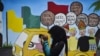 Seorang pemuda menggunakan ponselnya di depan mural kampanye Pemilu 2019, Banda Aceh, 17 Maret 2019. (Foto: AFP/CHAIDEER MAHYUDDIN)
